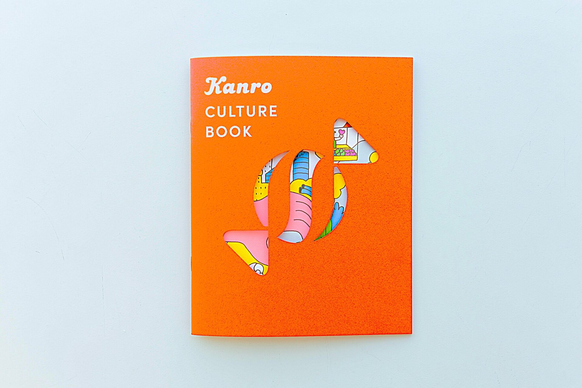 カンロが制作した「カルチャーブック」。表紙がカンロのコーポレートシンボルであるキャンディの形にくり抜かれている。中身は、カンロの未来予想図やカルチャーモデルの解説、ブランドパーソナリティやクレドの紹介などで構成されている。【撮影：栃久保誠】